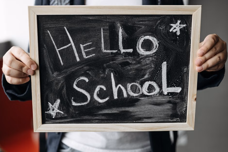 Close-up of hands holding a chalkboard with 'Hello School' message, perfect for back-to-school themes.
